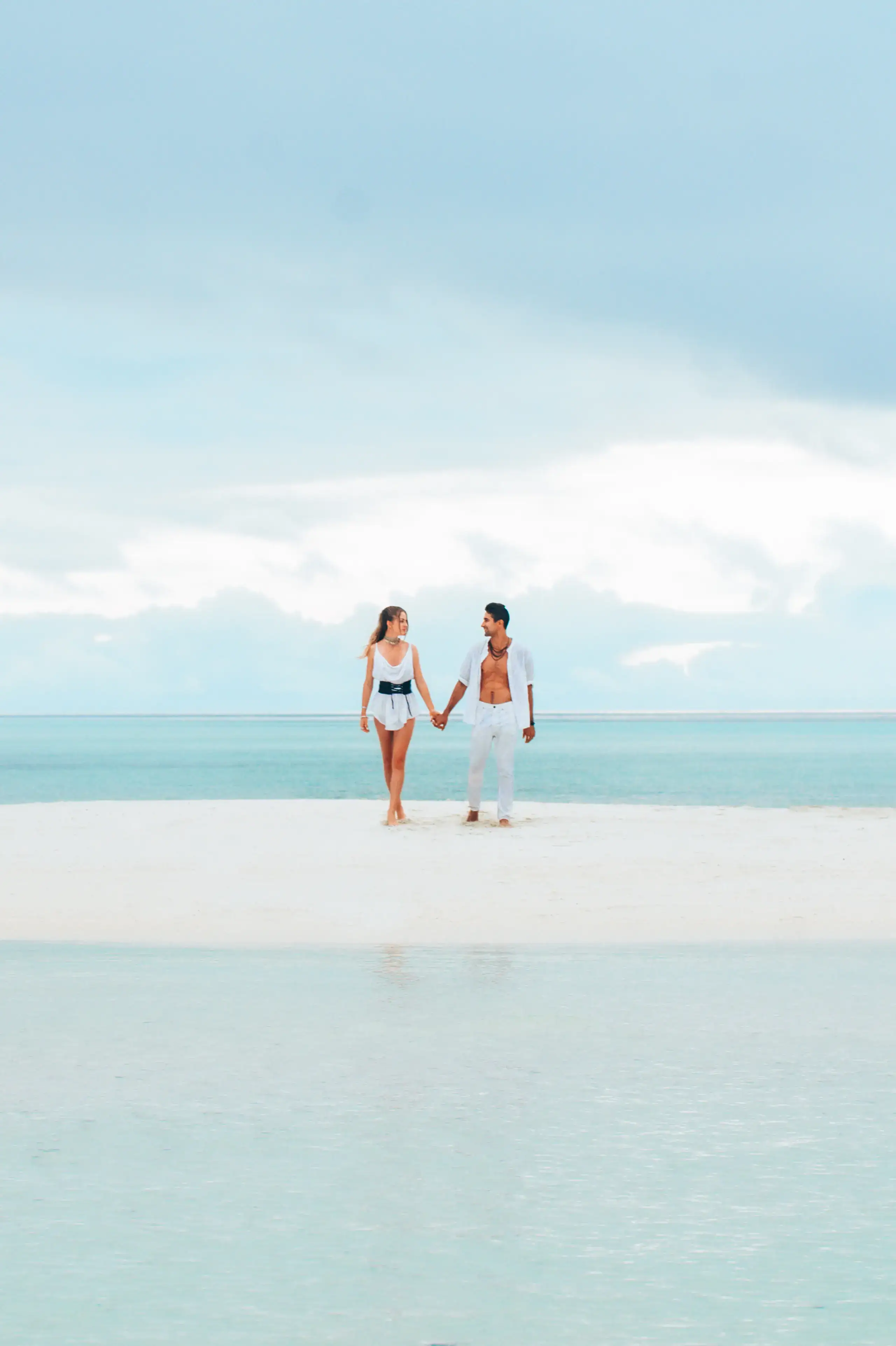 Couple walking on a white sandbar in turquoise water